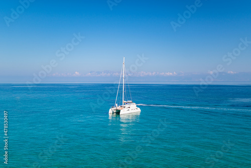 Yacht drifting on sea surface under blue cloudless sky