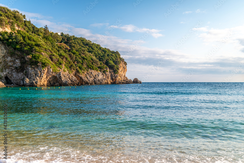 Calm beach of Mediterranean sea near high hill with forest