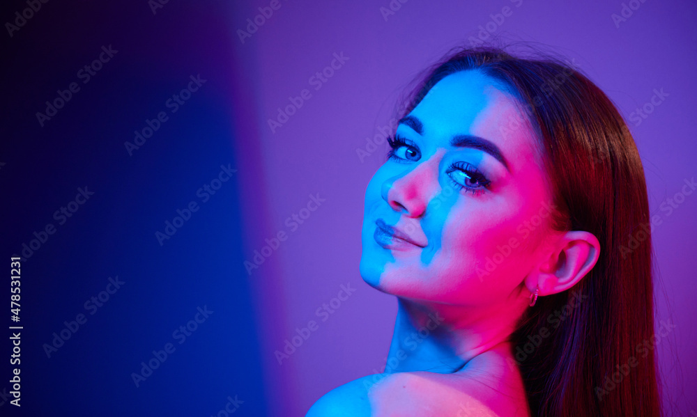 Close up view. Fashionable young woman standing in the studio with neon light