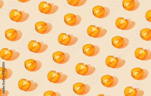 Fototapeta Naklejka Na Ścianę i Meble -  Creative pattern made of persimmon fruits on pastel background with sunlit. Healthy food concept. Minimal style
