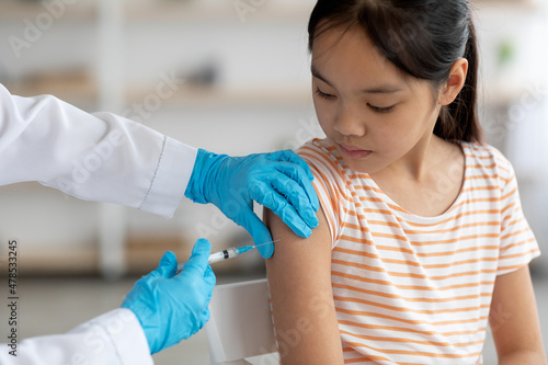 Unrecognizable doctor making vaccination for asian girl