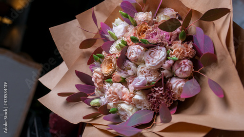 Photo of a bouquet of flowers in paper packaging on the table.