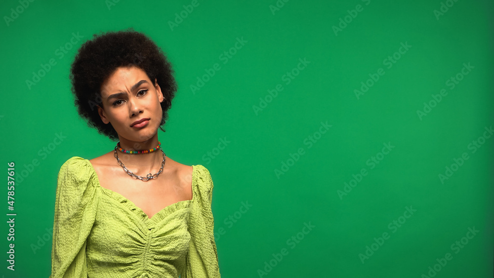 skeptical african american woman looking at camera isolated on green