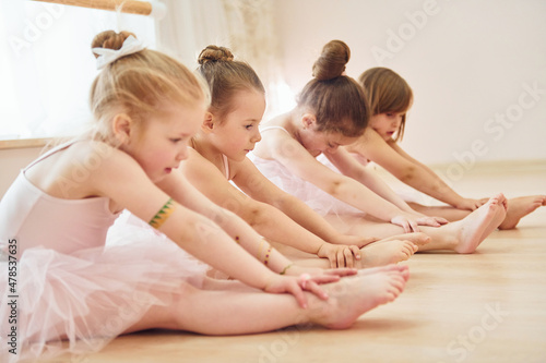 Fototapeta Stretching exercises. Little ballerinas preparing for performance