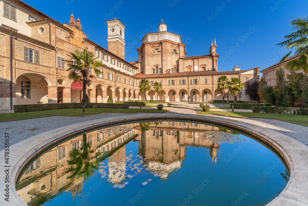 Cherasco, Cuneo, Italy - October 27, 2021: Monastery of Somaschi Fathers, in the background Sanctuary of Our Lady of the People (1702), baroque style church reflected in the park fountain