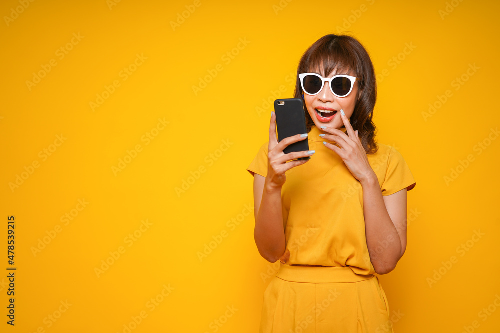 Young beautiful asian woman using smartphone to shopping online, get discount sale and shopaholic or news on a yellow background with surprised and shocked face, OMG Young beautiful asian woman using smartphone to shopping online, get discount sale and shopaholic or news on a yellow background with surprised and shocked face, OMG