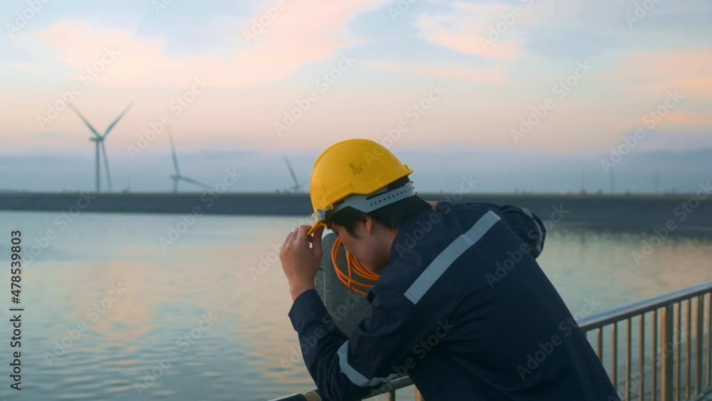 A male engineer wearing a protective helmet at sunset.. A male engineer wearing a protective helmet at sunset..