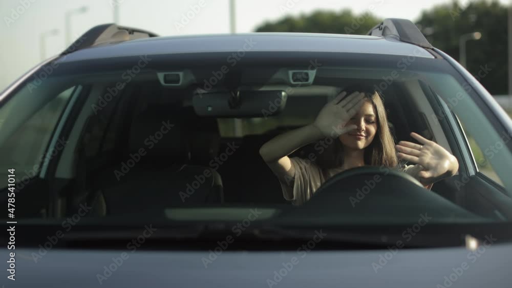 A happy woman is sitting in her car in the driver's seat. She is listening to music and dancing. She is waving her hands and enjoying the melody. 4K A happy woman is sitting in her car in the driver's seat. She is listening to music and dancing. She is waving her hands and enjoying the melody. 4K