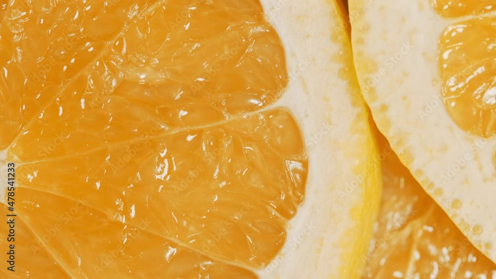 Slow motion of rotation ripe sliced oranges. Circles of fresh citrus as food background. Tropical fruits. Concept of proper nutrition or healthy lifestyle. Macro shot. Slow motion of rotation ripe sliced oranges. Circles of fresh citrus as food background. Tropical fruits. Concept of proper nutrition or healthy lifestyle. Macro shot.