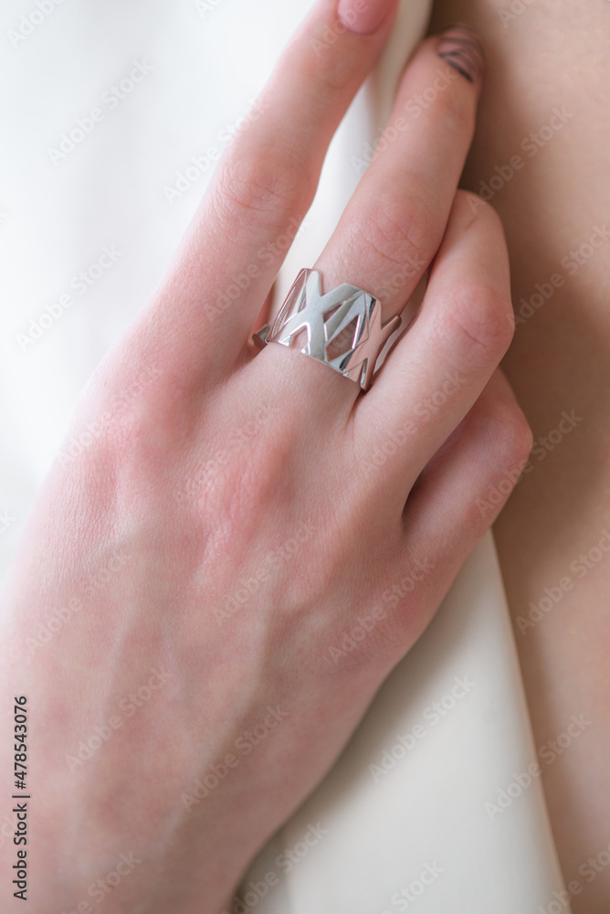 Trendy silver ring on a beautiful young girl in a white fashionable jacket. Beauty and fashion 
