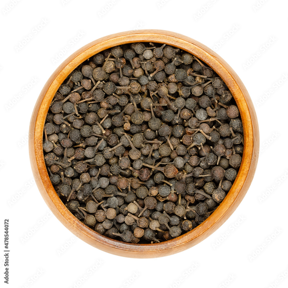 Cubeb berries, known as tailed pepper or Java pepper, in a wooden bowl. Dark brown berries, with their stalks still attached. Dried fruits of Piper cubeba, used as seasoning with mild pepper flavor. Cubeb berries, known as tailed pepper or Java pepper, in a wooden bowl. Dark brown berries, with their stalks still attached. Dried fruits of Piper cubeba, used as seasoning with mild pepper flavor.