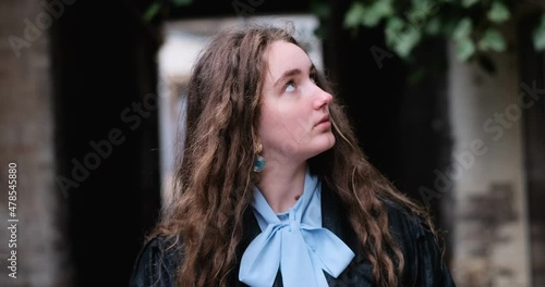 Young unsophisticated girl with natural brown curly hair looks around her in surprise. Innocent naive girl