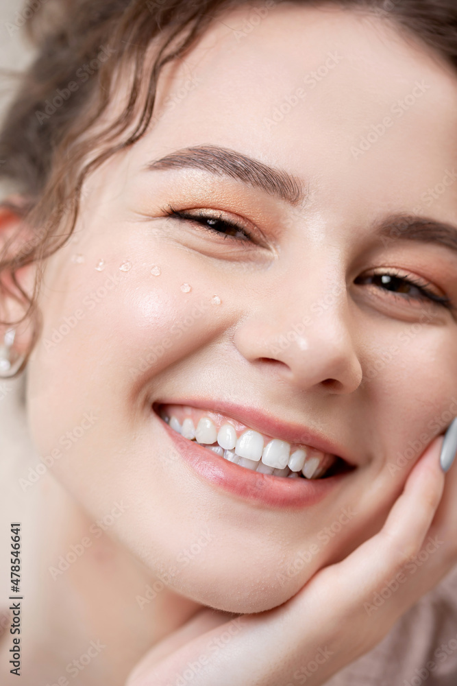 Closeup face Young pretty woman with curly hair smiles and looks into frame in robe, concept of cosmetology beauty salon Closeup face Young pretty woman with curly hair smiles and looks into frame in robe, concept of cosmetology beauty salon