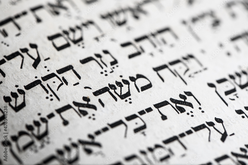 Closeup of hebrew word in Torah page that translates in english as Moses, name prophet in Judaism, leader of Israelites and lawgiver. Selective focus.