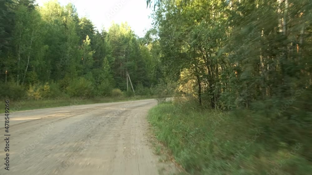 View from the moving car on the forest and countryside road at summer day. Tourism, traveling by car concept. The camera shakes and bounces because of the bad road with pits. View from the moving car on the forest and countryside road at summer day. Tourism, traveling by car concept. The camera shakes and bounces because of the bad road with pits.