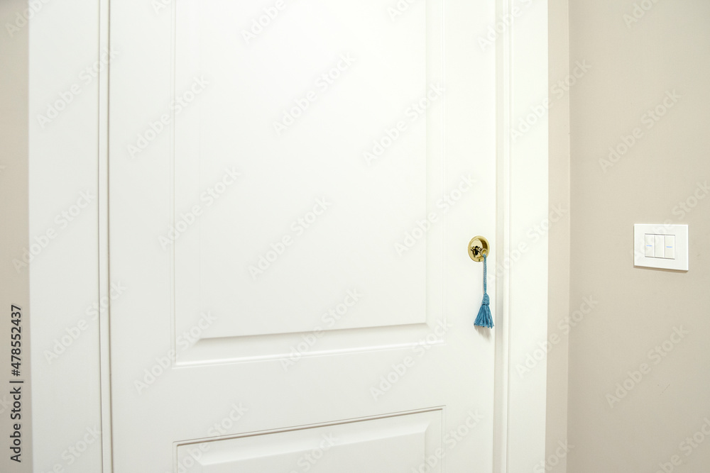 Detail of a sliding white door in the wall. The door is closed and the key has a decorative key ring. Detail of a sliding white door in the wall. The door is closed and the key has a decorative key ring.
