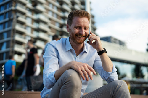 Businessman using the phone while sitting on the stairs. Happy man using the phone.