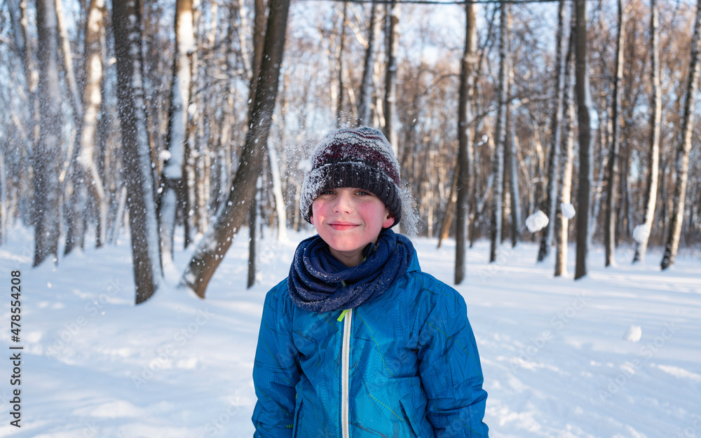 Portrait of a cheerful boy in a snow covered knitted hat against the background of a winter forest. Portrait of a cheerful boy in a snow covered knitted hat against the background of a winter forest.