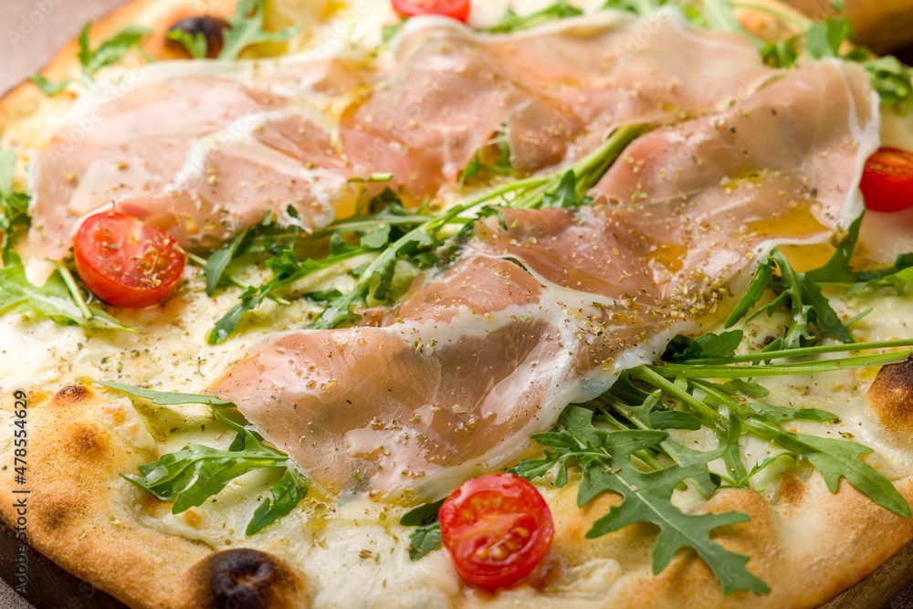 Pizza with Parma ham and arugula and tomatoes on the board macro close up, primavera Pizza with Parma ham and arugula and tomatoes on the board macro close up, primavera