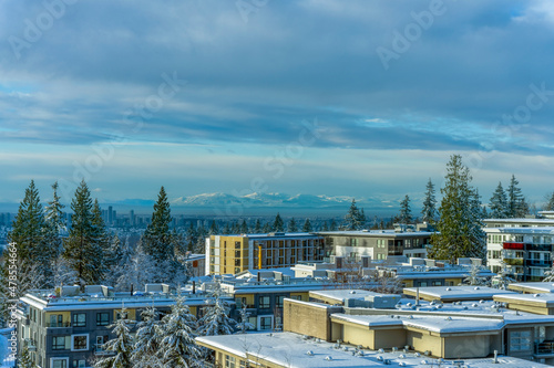 Crispy winter morning cityscape view from Univercity Highlands on Burnaby Mountain across high-rise city buildings to distant  alpine mountains on horizon. © Andrew