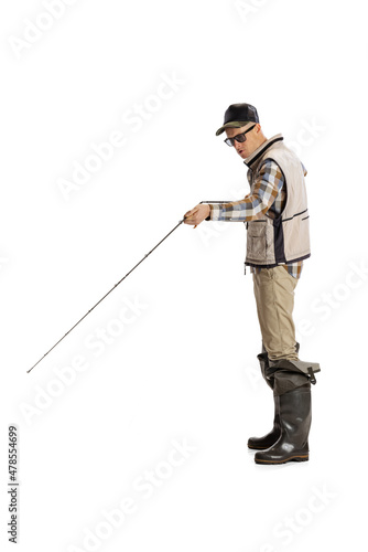 Portrait of young man, professional fisherman with fishing rod, spinning and equipment going to river isolated over white studio background