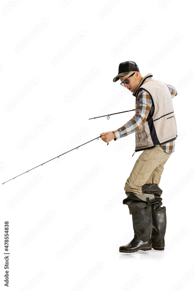 Portrait of young man, professional fisherman with fishing rod, spinning and equipment going to river isolated over white studio background Portrait of young man, professional fisherman with fishing rod, spinning and equipment going to river isolated over white studio background