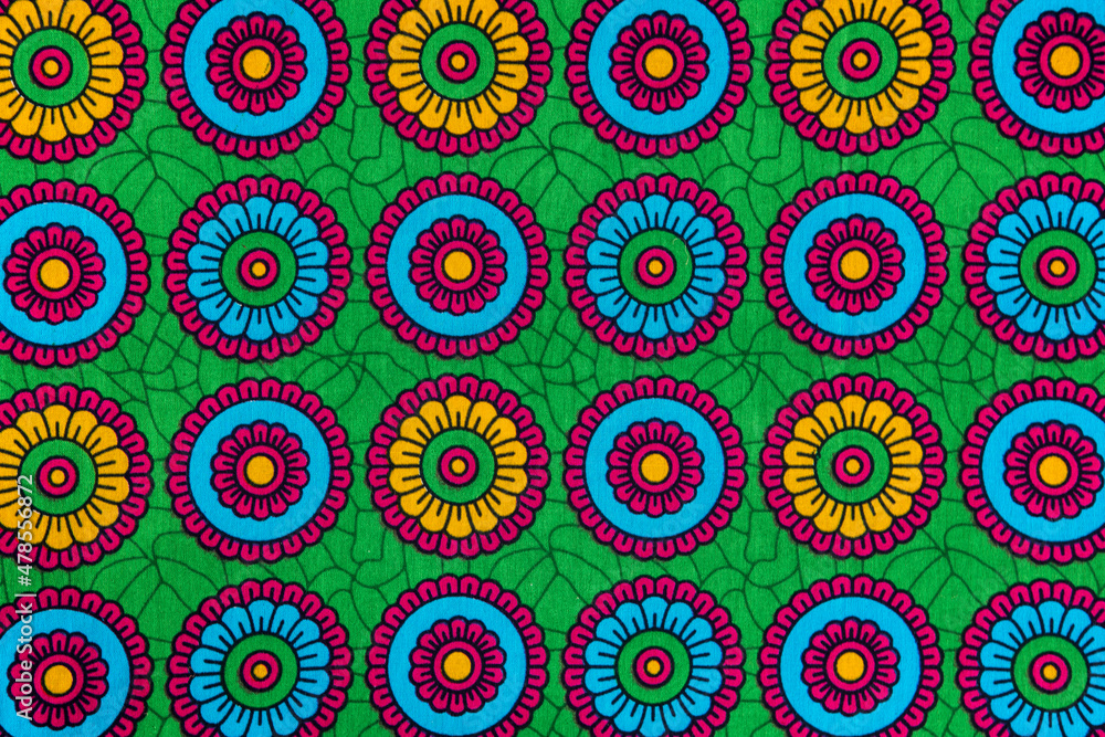 Fototapeta premium Colorful african printed textile close-up. Ethnic geometric pattern, fabric from Tanzania with abstract floral motif and vibrant colors.