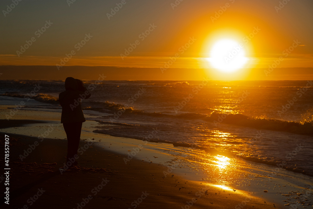 Woman enjoying sunset at beach in winter sunshine