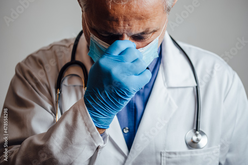 Stressed out and overworked doctor holding his nose bridge photo