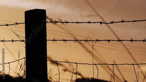 Sunset background and barbed wire fence silhouette  photo