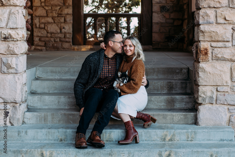 Trendy couple sitting on stairs with puppy Trendy couple sitting on stairs with puppy
