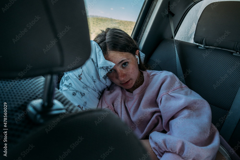 Teen girl relaxing in back of car on road trip Teen girl relaxing in back of car on road trip