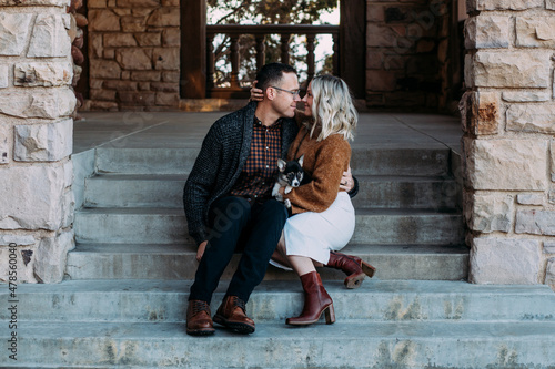 Young couple snuggling on steps with puppy