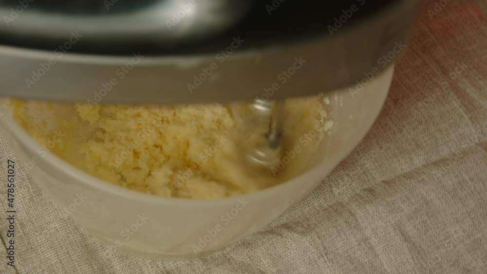 Unrecognizable person whisks dough in bowl with mixer. Unknown housewife preparing beaten dough. Close up. Concept of making dough for home baking. Unrecognizable person whisks dough in bowl with mixer. Unknown housewife preparing beaten dough. Close up. Concept of making dough for home baking.