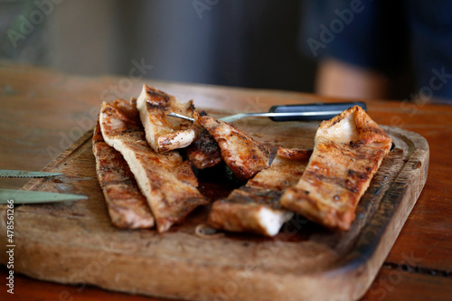 Grilled pork meat. Cooked meat. Food. Meal. Roast. Barbecue. Wooden plate with freshly cut meat slices. Argentinian barbecue. Food with proteins of animal origin. Knife and fork. photo