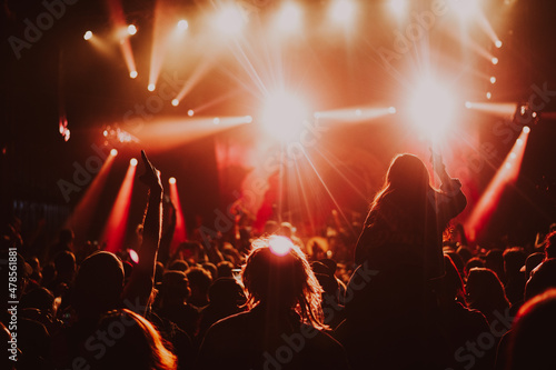 People at a rock concert dancing to the live band and music, with bright lights