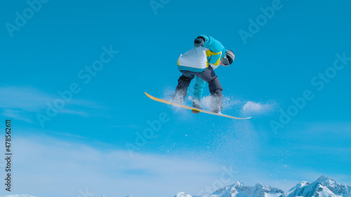 Fit male snowboarder doing a rotating grab while riding in Vogel ski resort