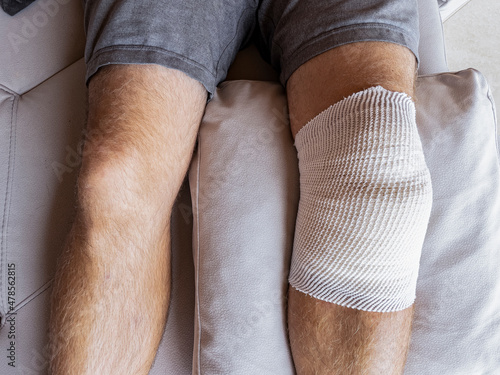 Photography CLOSE UP: Male patient's knee is wrapped in bandages after a meniscus surgery
