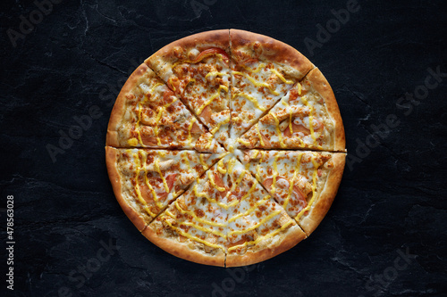 Pizza with chicken, cheese and tomatoes on a black stone background. Top view
