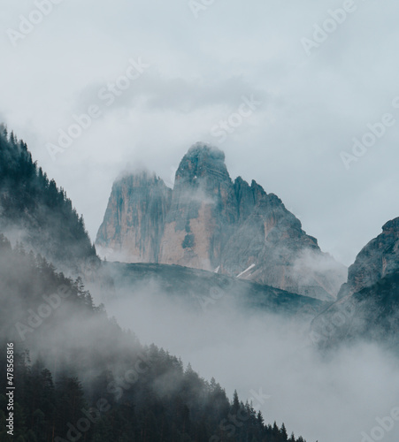 Misty landscape with fir forest, lake and mountain in hipster vintage retro style. Dolomity italy
