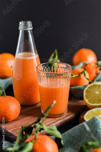 Frisch gepresster Orangensaft im Glas mit Citrusfrüchten auf dunklem Hintergrund. Fruchtiges Stillleben auf schwarzen Hintergrund mit frischen Früchten