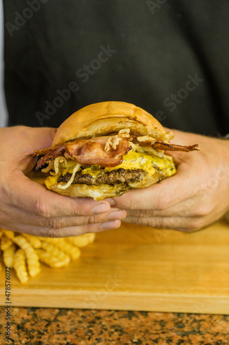 homemade burger cheddar bacon in hands © EstudioZopa