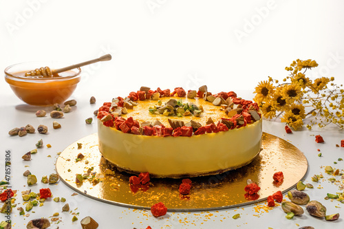 Beautiful raw mango cake with strawberry slices. Decorated with dried flowers and a dish with honey. photo