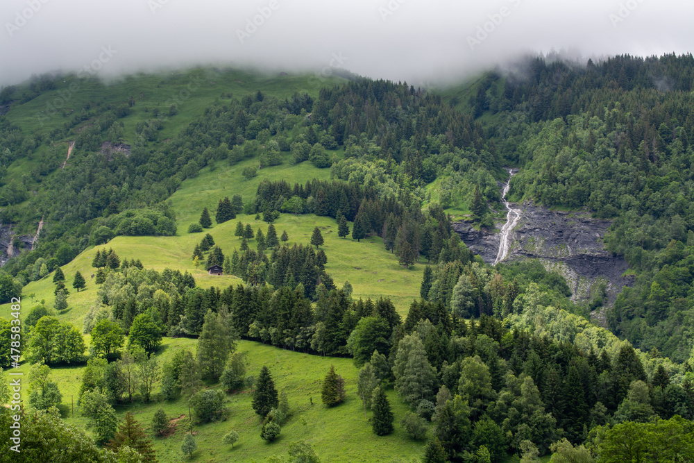 Obraz premium Panoramic view on mountain waterfalls, green forests and apline meadows near Saint-Gervais-les-Bains, Savoy. France