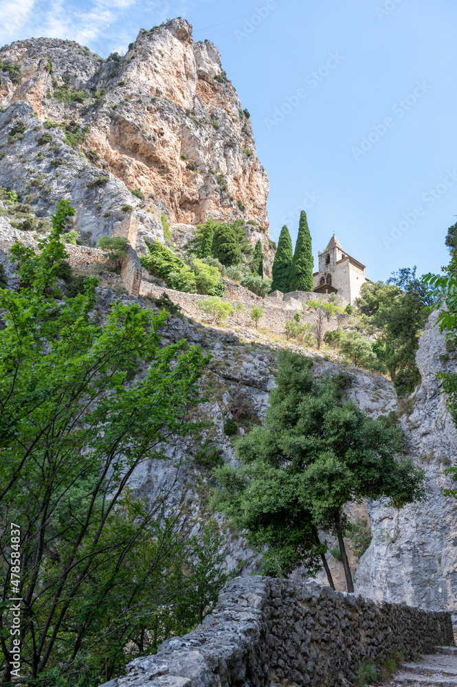 View on mountains cliff, old houses, green valley in remote medieval village Moustiers-Sainte-Marie in Provence, France
