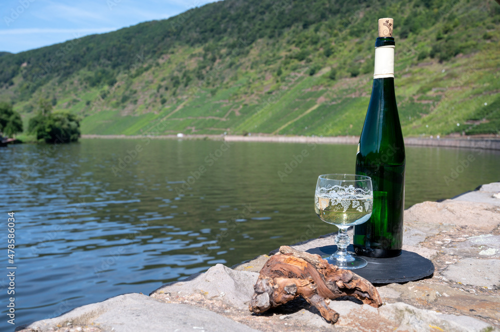Tasting of white quality riesling wine with view on steep slopes of vineyards overlooking Mosel river in sunny day Tasting of white quality riesling wine with view on steep slopes of vineyards overlooking Mosel river in sunny day