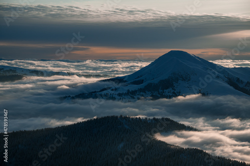 aerial view of snow covered mountain top and picturesque winter mountain landscape with coniferous trees and fog