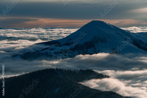 great aerial view of snow covered mountain top and picturesque winter mountain landscape with coniferous trees and fog