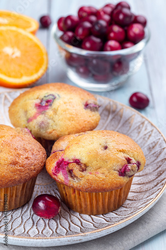 Cranberry orange muffins on wooden plate, vertical