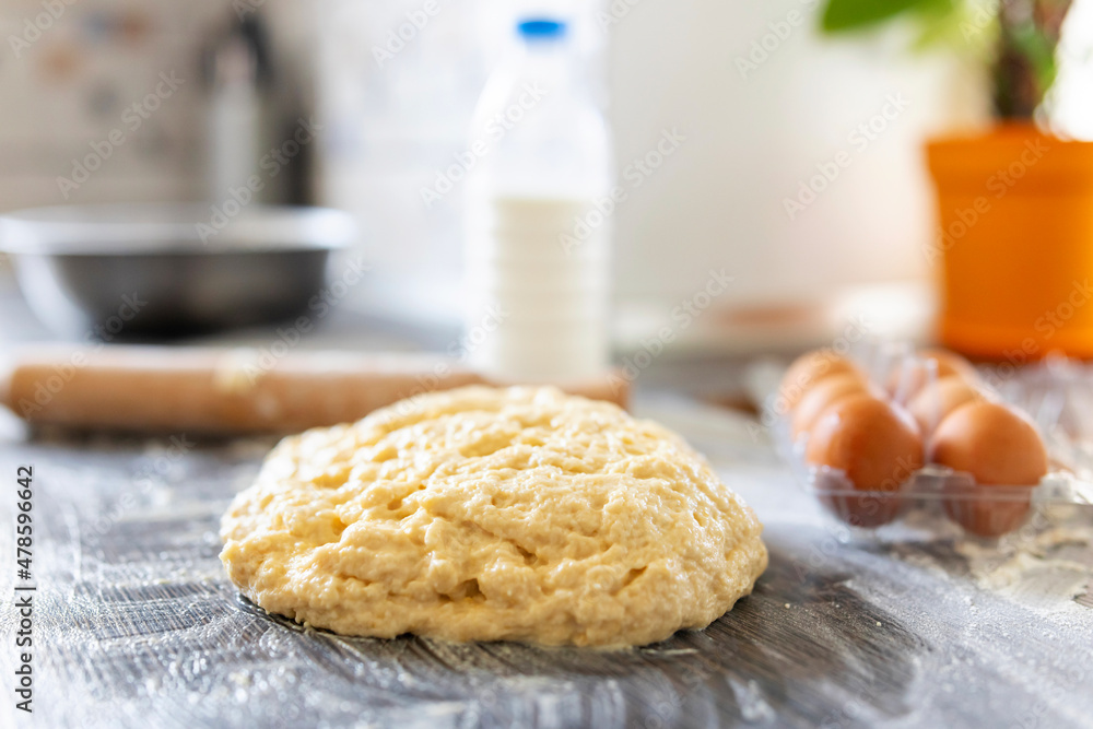 Homemade dough, rolling pin and baking ingredients on a dark wooden table in kitchen. Preparation of the dough Homemade dough, rolling pin and baking ingredients on a dark wooden table in kitchen. Preparation of the dough